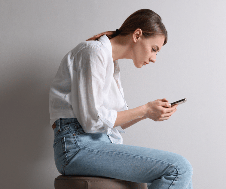 woman hunched over on her phone