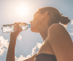 A woman drinking water on a sunny day