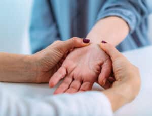 a massage therapist working on a client's wrist and hand