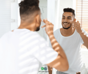 man applying cream to his face in a mirror